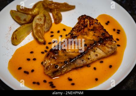 Pesce tradizionale alla griglia (spigola) con salsa di frutto della passione. Primo piano Foto Stock