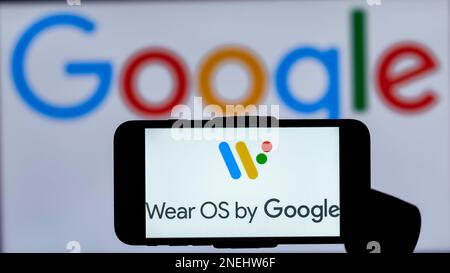 In questa immagine, il logo di Wear OS by Google viene visualizzato sullo schermo di un telefono cellulare con un logo Google sullo sfondo. Foto Stock