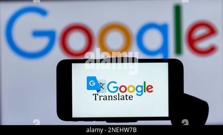 In questa immagine, il logo di Google Translate viene visualizzato sullo schermo di un telefono cellulare con un logo Google sullo sfondo. Foto Stock