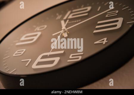 Basso angolo di primo piano di una parete di orologio analogica con profondità di campo ridotta Foto Stock
