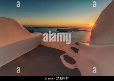 Il sole tramonta sulla caldera vista da una terrazza che si affaccia sul mare, Santorini Foto Stock