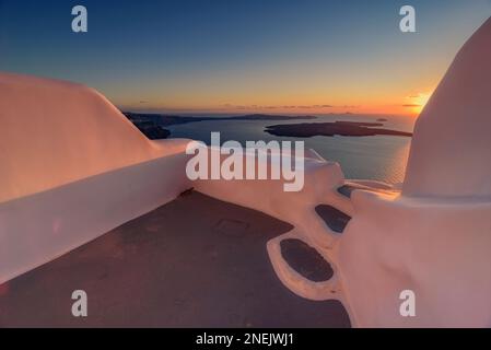 Il sole tramonta sulla caldera vista da una terrazza che si affaccia sul mare, Santorini Foto Stock