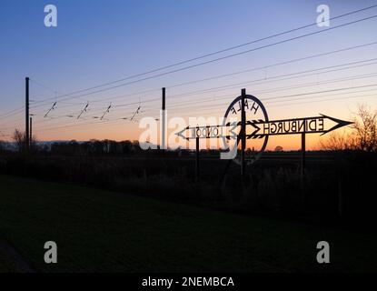 Newton on Ouse (Nord di York) da Londra a Edimburgo segnale a metà strada sulla costa orientale mainline che rende un tramonto silhouette Foto Stock