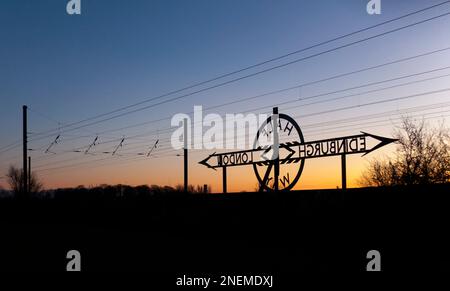 Newton on Ouse (Nord di York) da Londra a Edimburgo segnale a metà strada sulla costa orientale mainline che rende un tramonto silhouette Foto Stock