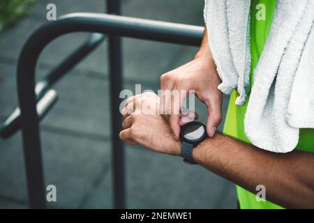 Uomo irriconoscibile che controlla il suo orologio intelligente dopo cardio Foto Stock