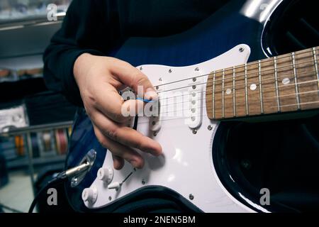 Primo piano della mano di un uomo che suona una chitarra elettrica Foto Stock