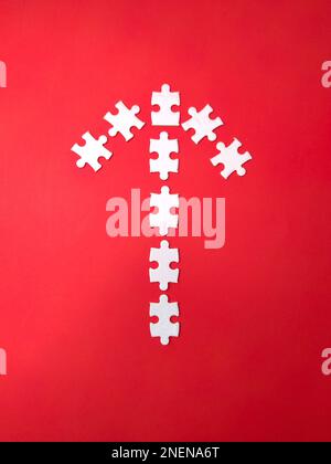 Alcuni puzzle bianchi disposti secondo la forma di frecce su uno sfondo rosso Foto Stock