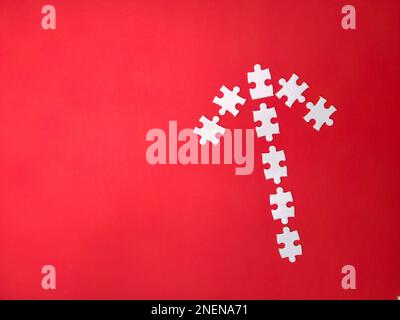 Alcuni puzzle bianchi disposti secondo la forma di frecce su uno sfondo rosso Foto Stock