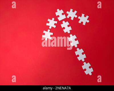 Alcuni puzzle bianchi disposti secondo la forma di frecce su uno sfondo rosso Foto Stock