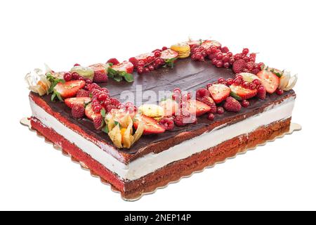 Torta di velluto rosso rettangolare. Glassa al cioccolato. Decorazione con frutta e amaretti. Su sfondo bianco. Foto Stock