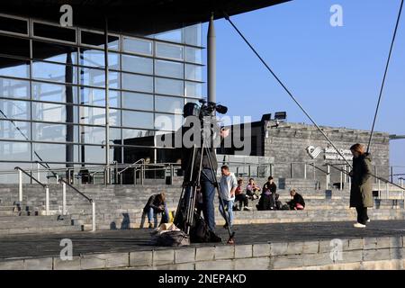 Filmare un pezzo-a-telecamera all'esterno dell'edificio Senedd, la baia di Cardiff. Uomo di macchina fotografica e intervistatore. Febbraio 2023. Inverno Foto Stock