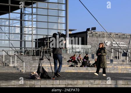 Filmare un pezzo-a-telecamera all'esterno dell'edificio Senedd, la baia di Cardiff. Uomo di macchina fotografica e intervistatore. Febbraio 2023. Inverno Foto Stock