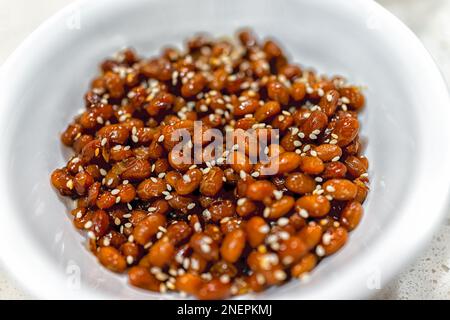 Macro closeup di semi di soia giapponesi asiatici con semi di sesamo e salsa di soia natto piatto di soia fermentato in piatto ciotola Foto Stock