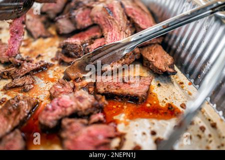 Evento con catering per bistecche brasiliane con vassoio a buffet per banchetti e pinze in metallo per churrascaria che servono bistecche di carne alla griglia con il famoso controfiletto picanha Foto Stock