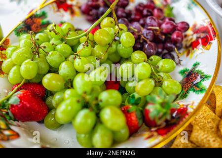 Uva verde uva frutta con cibo intero rosso closeup su piatto ciotola party piatto e fragole Foto Stock