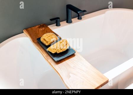 Vasca da bagno in legno mensola portadocumenti in bagno allestimento modello casa casa casa con spugna loofah scrubber in camera moderna di lusso bianco Foto Stock