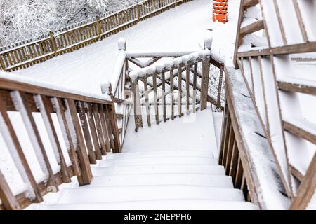 POV a piedi giù coperta di neve bianca casa coperta ponte di legno con ringhiera recinzione in inverno e passi per cortile nel nord della Virginia, Fairfax contea Foto Stock