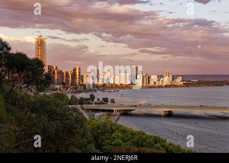 Vista sul centro di Perth nell'Australia Occidentale, paesaggio con grattacieli, parchi e baia con il ponte durante il tramonto o l'alba. Nuvole sul th Foto Stock