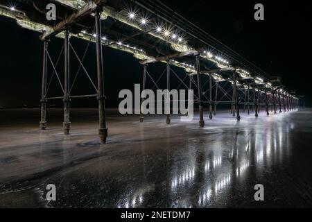 Luci riflesse nella sabbia bagnata di notte Foto Stock