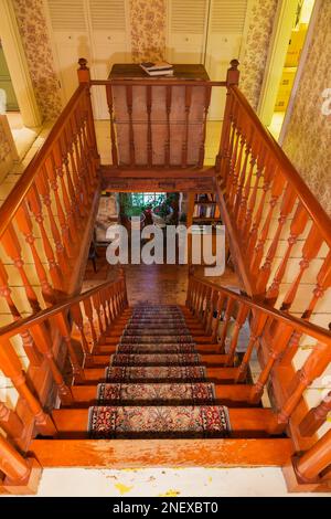 Scala in legno di pino colorato con tappeto e ringhiere sul corridoio del piano superiore con pavimenti in legno di pino dipinto di bianco all'interno della vecchia casa del 1820. Foto Stock