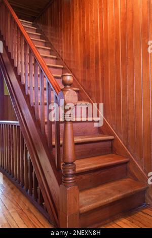 Scala in legno che conduce alla mansarda al piano superiore con pareti in legno di pino colombiano all'interno di una vecchia casa americana di 1927 quattro piazze. Foto Stock