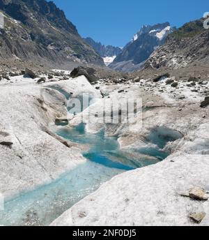 Il torrente glaciale sul ghiacciaio Mer de Glace con il Garand Jorasses sullo sfondo. Foto Stock