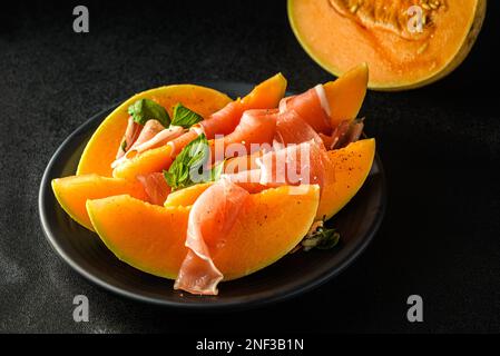 melone con parma su sfondo scuro. Foto di alta qualità Foto Stock