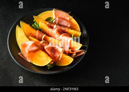 melone con parma su sfondo scuro. Foto di alta qualità Foto Stock