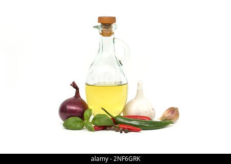 Olio in decanter di vetro, cipolla rossa, peperoncino, rametto di basilico e bulbo d'aglio isolato su fondo bianco. Spezie e tema aromatizzante ancora vita Foto Stock