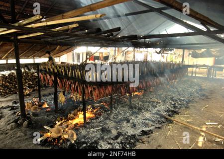 Le carni di tonno dello skipjack sono affumicate usando le bucce di cocco come combustibile che brucia ad un'industria domestica in Bitung, Sulawesi del nord, Indonesia. Popolarmente conosciuto come 'cakalang fufu', il tonno affumicato è considerato un 'cibo indigeno esotico' da un team di ricercatori guidati da Henny A. Dien (Facoltà di pesca e Scienze marine, Sam Ratulangi University, Manado) nel loro articolo pubblicato per la prima volta su Media Teknoi Hasil Perikanan nel gennaio 2020. La produzione di tonnidi da pesca rappresenta una delle attività economiche più importanti nella zona di Bitung City, dove circa il 20% degli abitanti opera in questo settore; Foto Stock