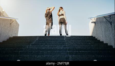 Non ci sono ascensori per il fitness, prendi le scale. Foto retroversa di un giovane uomo e di una donna che corrono su scale insieme in città. Foto Stock