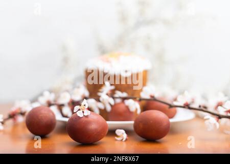Torta di Pasqua, uovo dipinto e ramo fiorito, composizione primaverile su tavola di legno Foto Stock