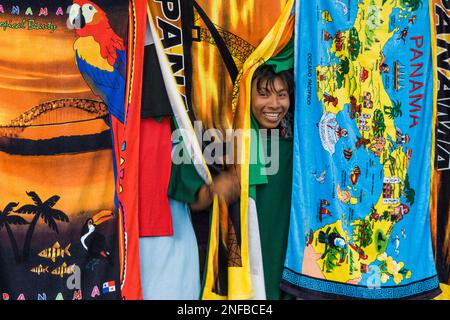 Una giovane Guna indigena, o Cuna, ragazzo che vende cioloranti asciugamani da spiaggia raffiguranti scene di Panama sulla strada a Portobelo, Panama. Foto Stock