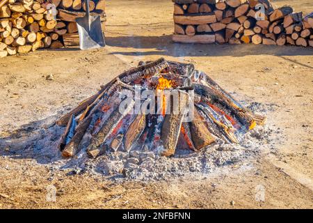 Cima di un grande falò circolare imballato con legna da ardere sui lati che il fumo proviene dai tronchi di legno in una festa popolare villaggio per la rura tipica Foto Stock