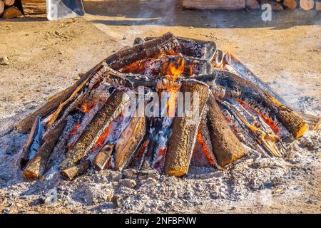 Cima di un grande falò circolare imballato con legna da ardere sui lati che il fumo proviene dai tronchi di legno in una festa popolare villaggio per la rura tipica Foto Stock