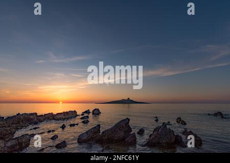 Il sole tramonta dietro l'isolotto di Isola delle femmine, in Sicilia Foto Stock