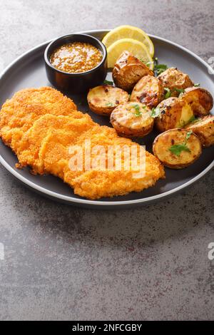 Le cotolette di vitello Munchner Schnitzel vengono spazzolate con una combinazione di senape dolce e rafano prima ricoperte di farina, uova e pangrattato, quindi fritte Foto Stock