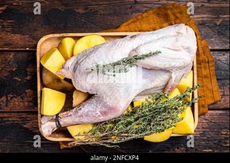 Faraona cruda fresca, faraona con patate, selvaggina. Sfondo di legno. Vista dall'alto. Foto Stock