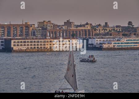 Luxor, Egitto tramonto girato dalla riva ovest mostrando il fiume Nilo con Felucche, navi da crociera e Luxor Tempio in riva est Foto Stock