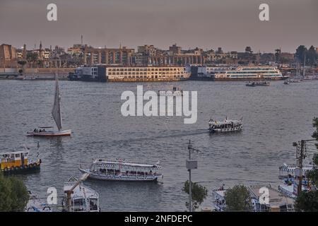 Luxor, Egitto tramonto girato dalla riva ovest mostrando il fiume Nilo con Felucche, navi da crociera e Luxor Tempio in riva est Foto Stock