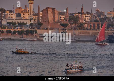 Luxor, Egitto tramonto girato dalla riva ovest mostrando il fiume Nilo con Felucche, navi da crociera e Luxor Tempio in riva est Foto Stock