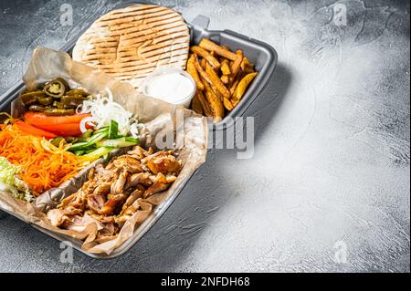 Doner kebab Shawarma su un piatto con patatine fritte e insalata in scatola per andare, da asporto. Sfondo bianco. Vista dall'alto. Spazio di copia. Foto Stock