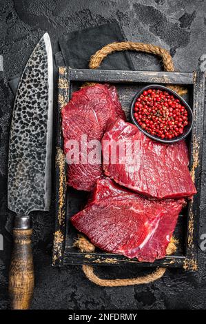 Venison crudo crudo crudo Carne cara, carne di selvaggina. Sfondo nero. Vista dall'alto. Foto Stock