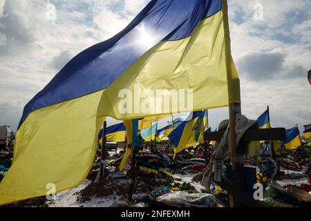 KHARKIV, UCRAINA - 16 FEBBRAIO 2023 - le bandiere nazionali volano sopra le tombe dei difensori ucraini periti sul vicolo di Gloria al cimitero N18, Khar Foto Stock