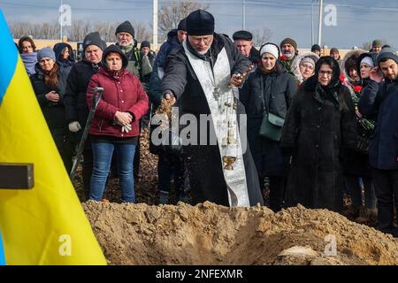 KHARKIV, UCRAINA - 16 FEBBRAIO 2023 - Un sacerdote attraverso il suolo nella tomba di Euromaidan attivista, vice comandante ospedale Hennadii Kovshyk durante Foto Stock