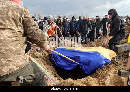 KHARKIV, UCRAINA - 16 FEBBRAIO 2023 - gli uomini abbassano la bara dell'attivista Euromaidan, vice comandante dell'ospedale Hennadii Kovshyk coperto con un ucraino Foto Stock