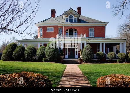 HICKORY, NC, USA-14 FEB 2023: Casa in mattoni in stile revival greco vicino al centro. Vista frontale. Sole, cielo blu giorno. Foto Stock