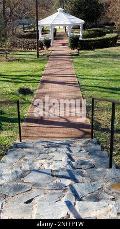 HICKORY, NC, USA-14 FEB 2023: Glenn Hilton City Park, scalinata rocciosa e passeggiata in mattoni che conduce al gazebo bianco. Foto Stock