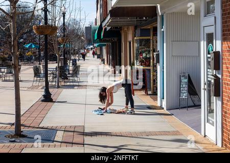 HICKORY, NC, USA-14 FEB 2023: Giovane donna che fotografa vestiti sul marciapiede soleggiato. Foto Stock