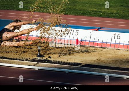 atterraggio in sabbia atleta maschile salto triplo Foto Stock